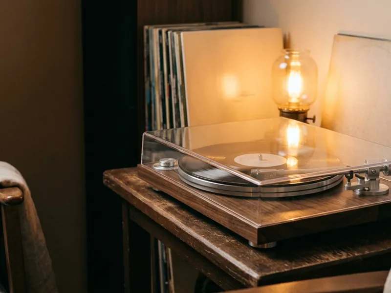 A compact turntable with a clear dust cover on a side table